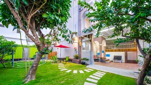 A well-maintained garden with a patio area, outdoor seating, and a red umbrella. - Chi's House (Taitung)