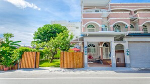 A multi-story building with a balcony, a gated entrance, and a red umbrella. - Chi's House (Taitung)