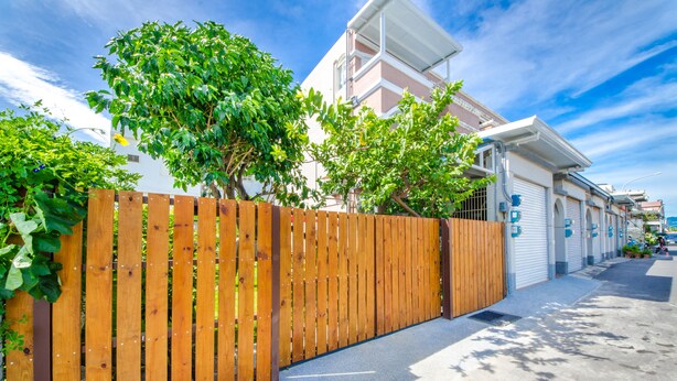 A residential street with a wooden fence, a garage, and a clear blue sky. - Chi's House (Taitung)