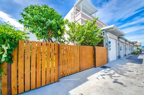 A residential street with a wooden fence, a garage, and a clear blue sky. - Chi's House (Taitung)