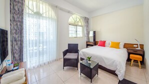 A hotel room with a bed, a chair, a small table with a plant, a TV, and a window with curtains. - Chi's House (Taitung)