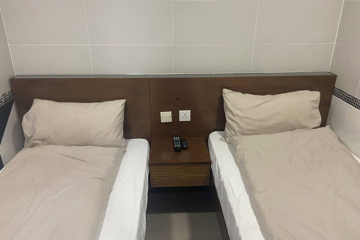 A double bed with a wooden headboard, two bedside tables, and a control panel on the wall.