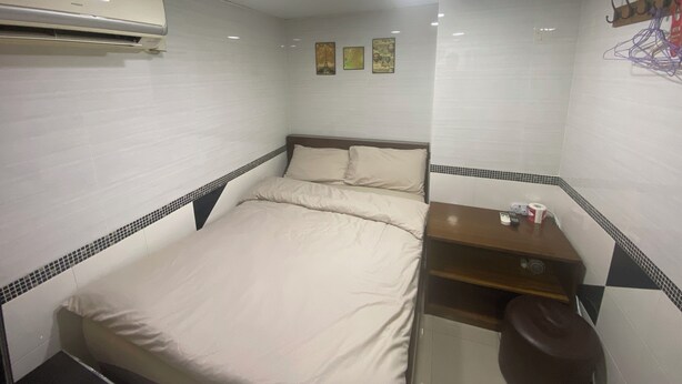 Ein kleines, ordentlich eingerichtetes Hotelzimmer mit einem Bett, einem Schreibtisch und einem Stuhl.