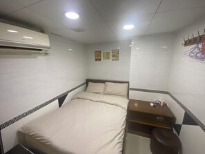 Une petite chambre d’hôtel, bien aménagée et comprenant un lit, un bureau et une chaise.