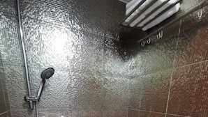 Ein kleines, modernes Badezimmer mit Toilette, Duschkopf und Handtuchhalter.