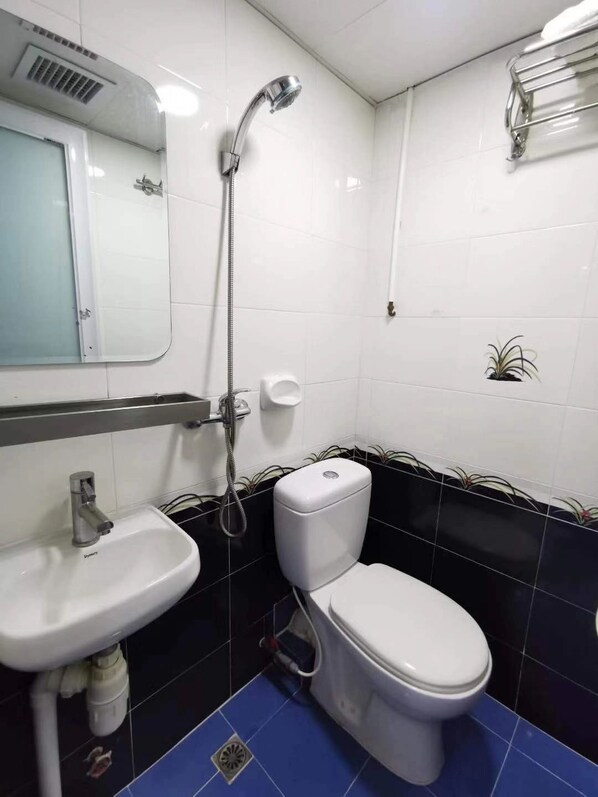Une salle de bain avec un lavabo blanc, des toilettes et une douche.