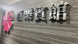 Ein Schild mit chinesischen Schriftzeichen und einem stilisierten Blütenlogo.