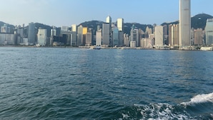 Horizontale Skyline mit modernen Gebäuden und einem Gewässer im Vordergrund.