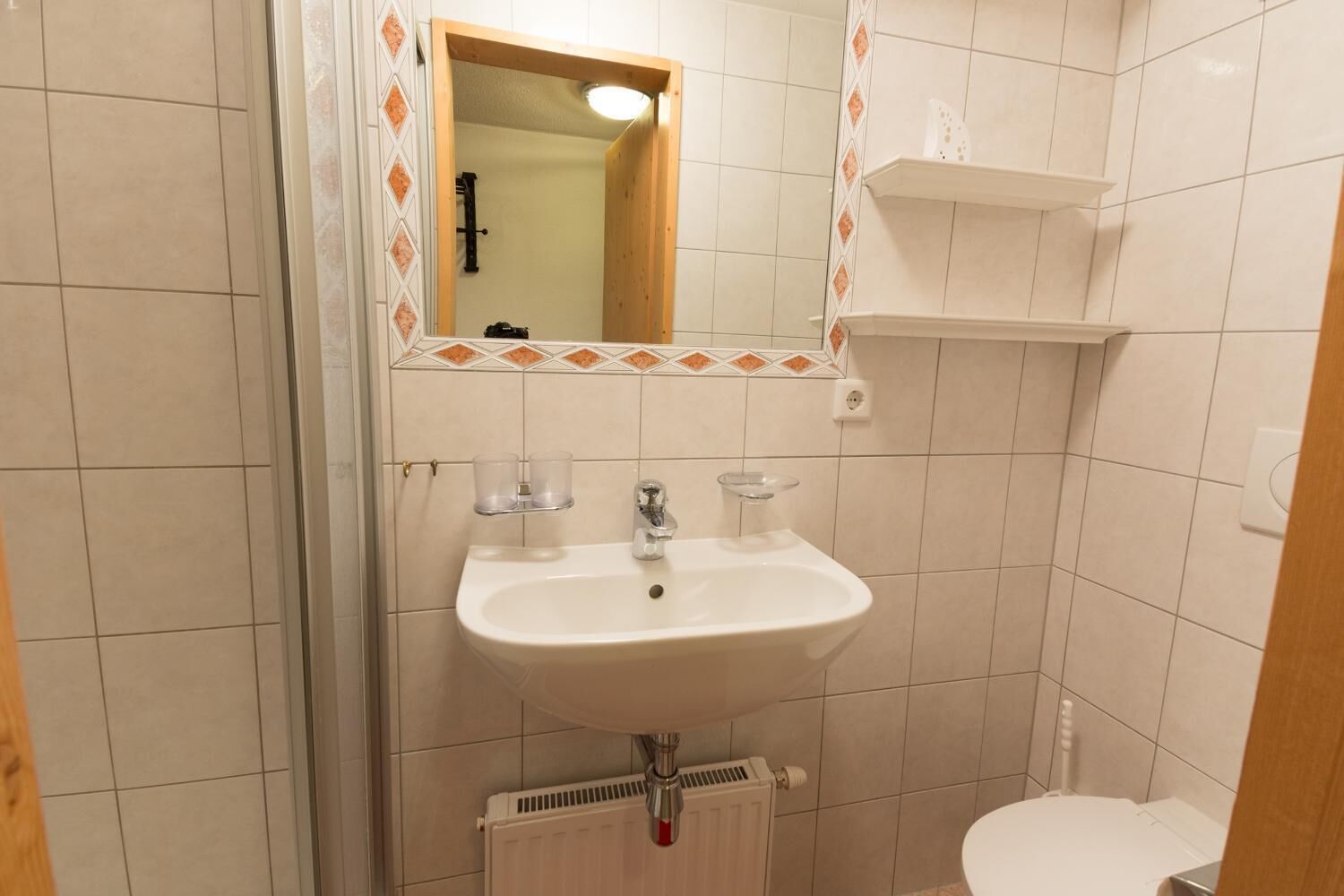 A bathroom with a white sink, a mirror, a toilet, and a radiator.