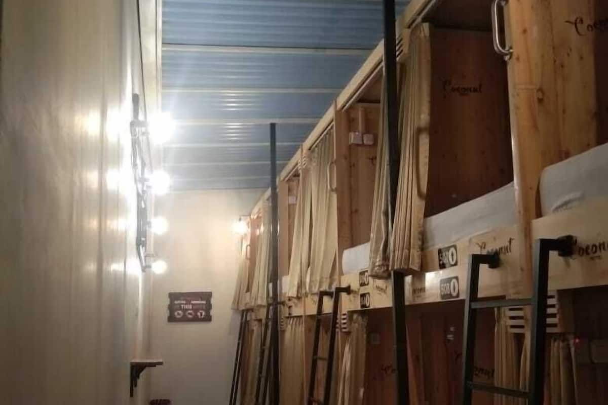 A corridor with bunk beds, checkered floor, and overhead lights.