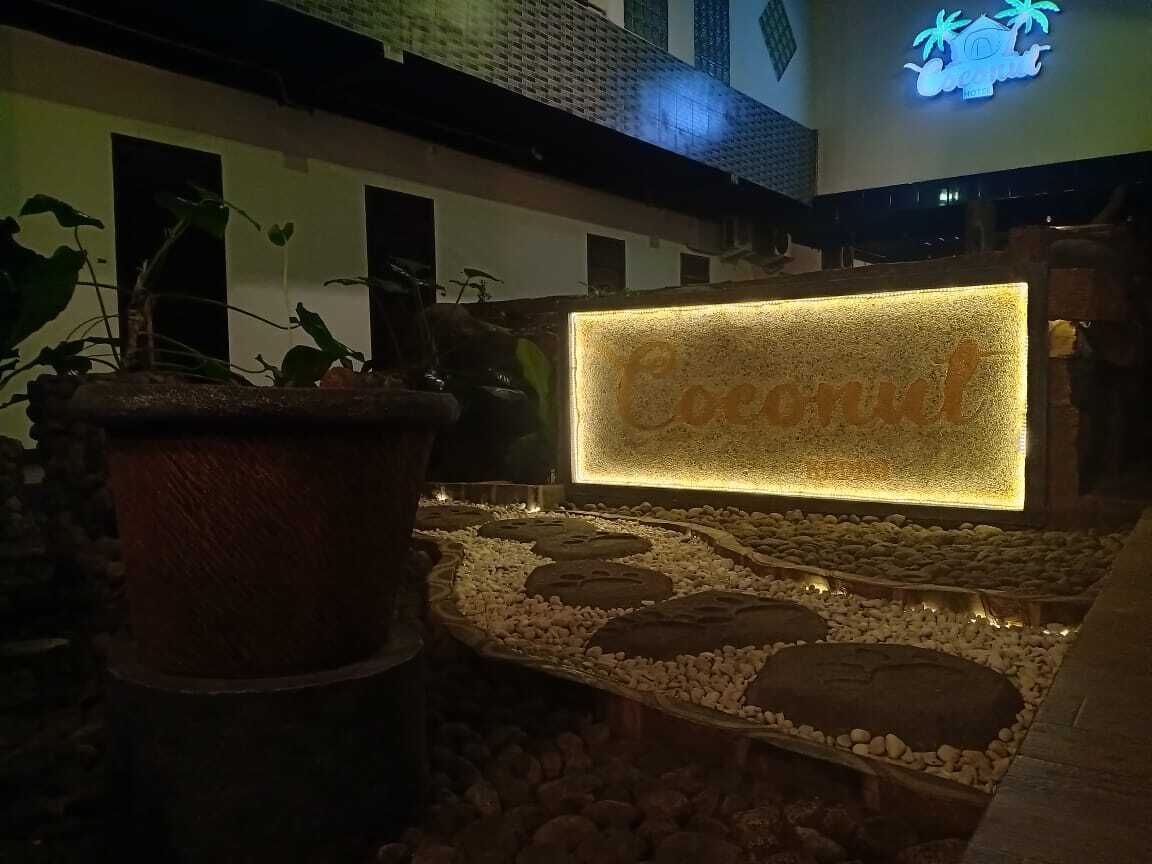 A well-lit area with a 'Coconut' sign, potted plants, and a stone pathway.