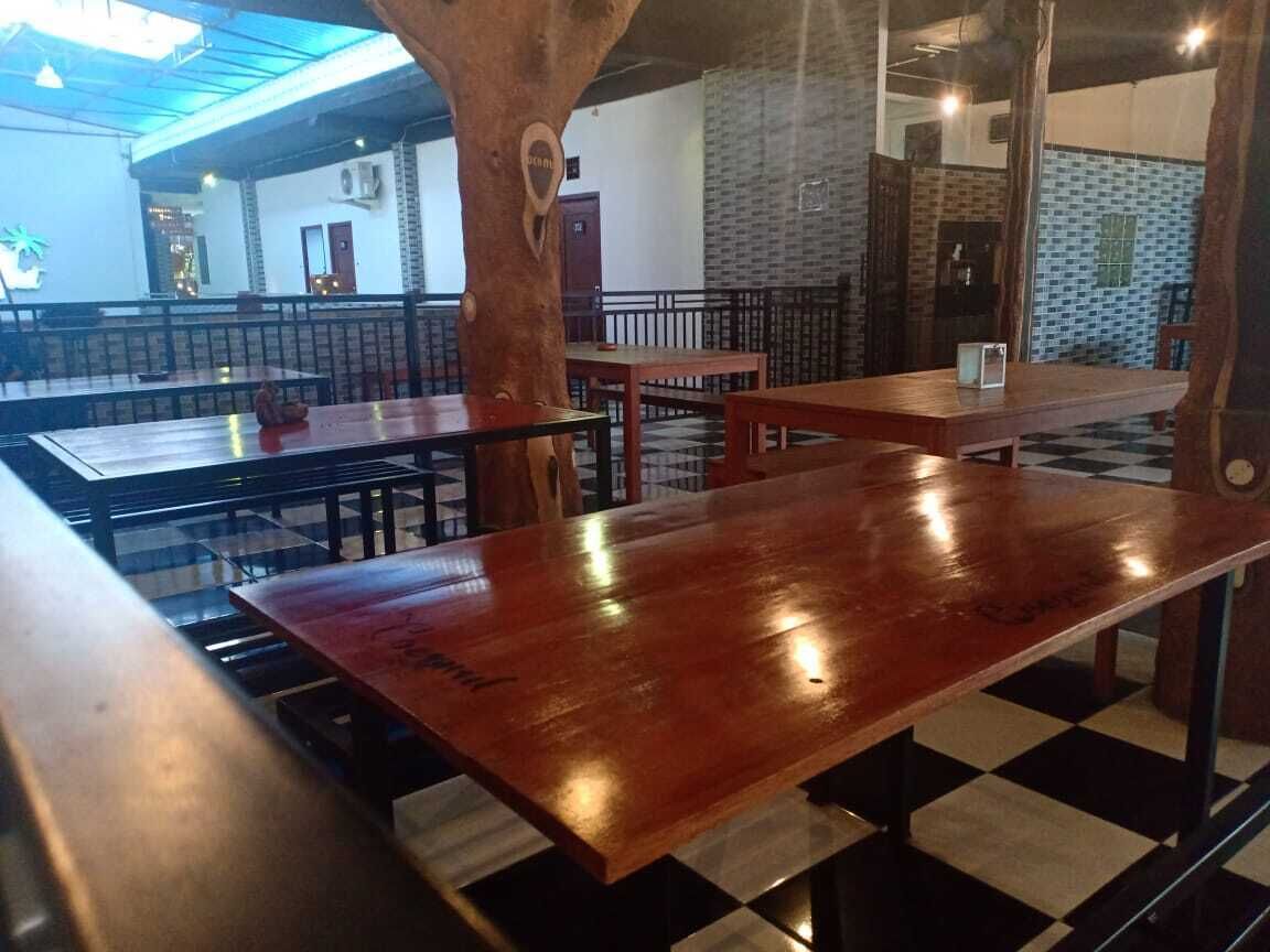 Een restaurant met houten tafels en banken, een geruit vloertje en een bakstenen muur.