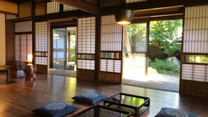 Een traditionele Japanse kamer met tatami vloerbedekking, shoji schermen en een lage tafel met kussens.