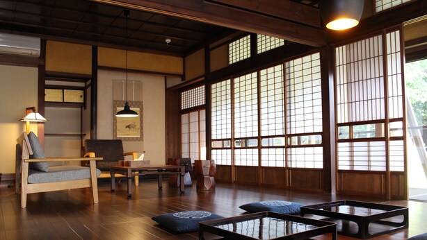 Een traditionele Japanse kamer met tatami vloerbedekking, lage houten tafels, kussens en verschuifbare shoji deuren.