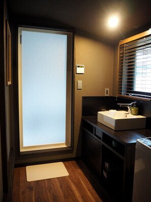 Een kleine badkamer met een groot geëtst glazen raam, een wastafel en een spiegel.