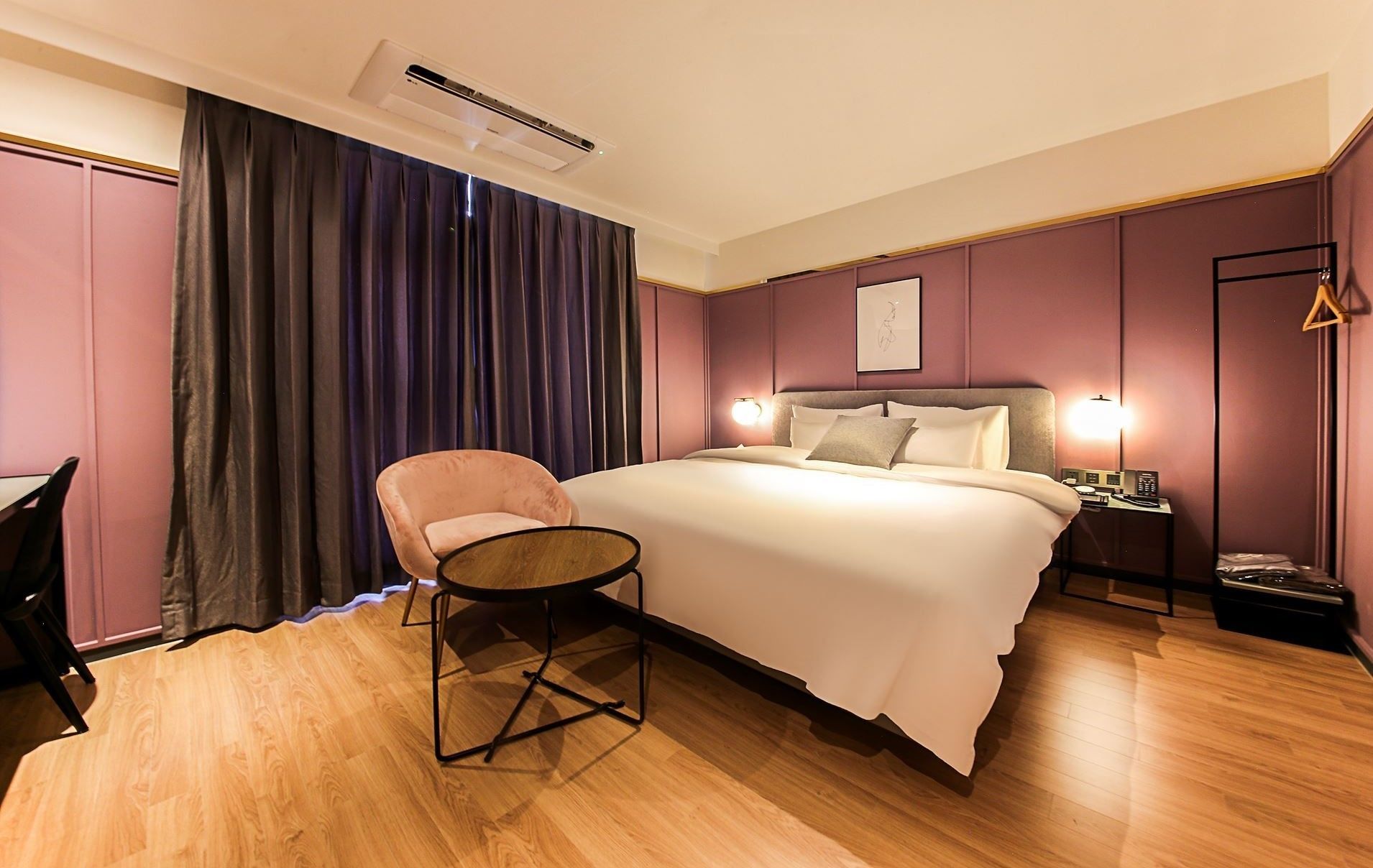 Una habitación de hotel con una cama, una silla, un escritorio y una mesita de noche con una lámpara.