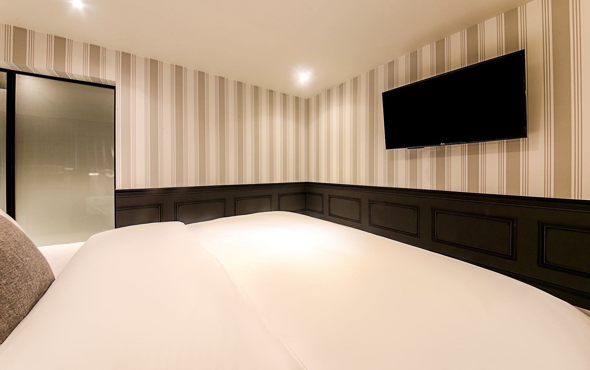 A hotel room with a large bed, a flat-screen TV mounted on the wall, and a sliding door.