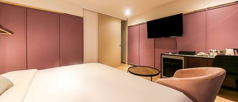 Habitación de hotel moderna con una cama grande, un escritorio con televisor de pantalla plana y una silla rosa.