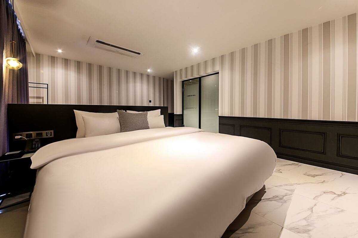 Een moderne hotelkamer met een groot bed, een nachtkastje met een lamp en een kledingkast.