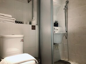 Un baño moderno con cabina de ducha de vidrio, un lavabo blanco y un inodoro.