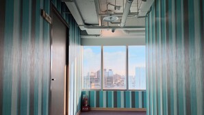 A hallway with striped walls, a fire extinguisher, and a window with a city view. - Jia Inn (Tainan)