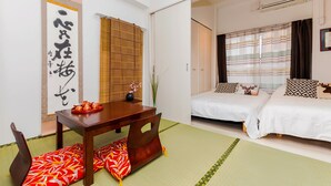 A hotel room with a traditional Japanese aesthetic, featuring tatami flooring, a low wooden table, and a bed with patterned pillows. - 7mins Shinsaibashi Comfortable Apartment (Osaka)