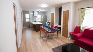 Eine moderne Wohnung mit Essbereich, Küche und einem roten Sofa.