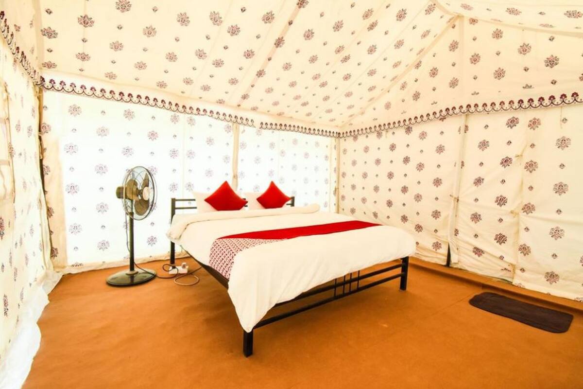Une chambre à coucher avec un lit, une table de chevet, un ventilateur et une fenêtre.