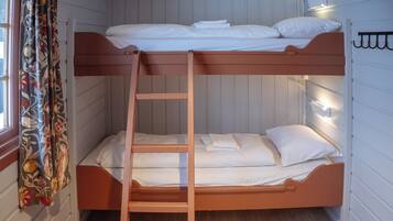 A bunk bed room with a ladder, white bedding, and a curtain with a floral pattern.
