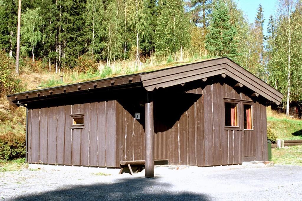 A small, single-story wooden cabin with a sloped roof, a window on each side, and a door in the center.