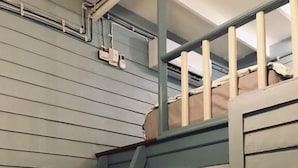 A staircase with wooden steps and a metal railing, leading to a landing with a light fixture. - Lhong Yaowarat Hostel (Bangkok)