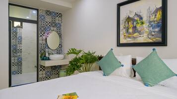 A hotel room with a bed, a bathroom with patterned tiles, a sink, and a framed painting on the wall.