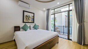 A hotel room with a large bed, a painting on the wall, and a balcony with curtains. - Onion Homestay (Da Nang)