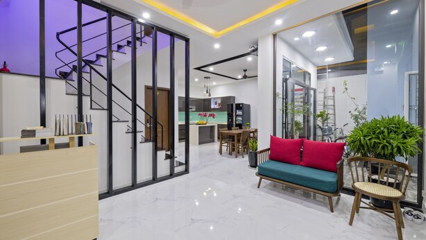 A modern interior with a reception desk, a staircase, a dining area, and a seating area with a sofa and chairs. - Onion Homestay (Da Nang)