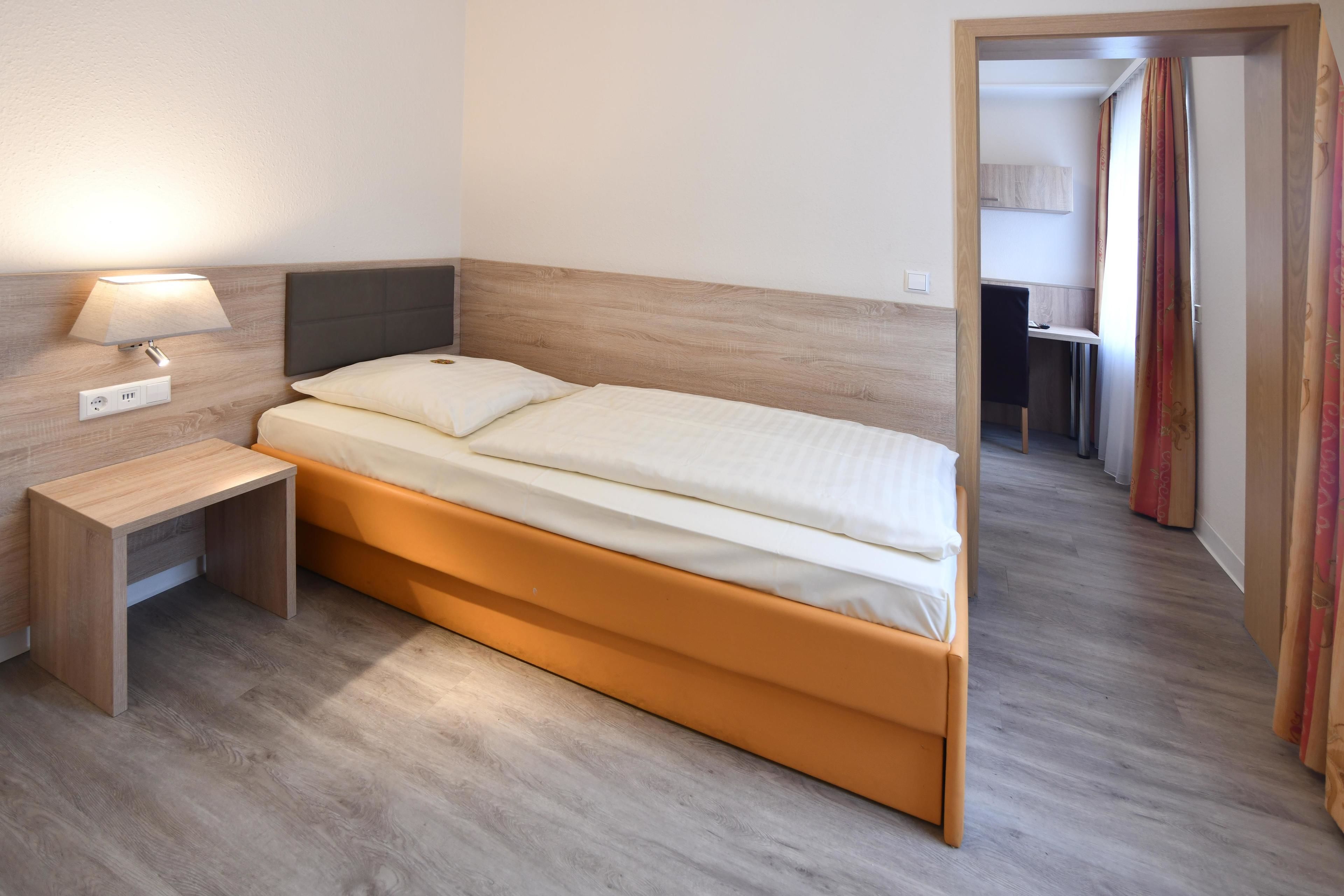 Una habitación de hotel con una cama, una mesita de noche y una lámpara.