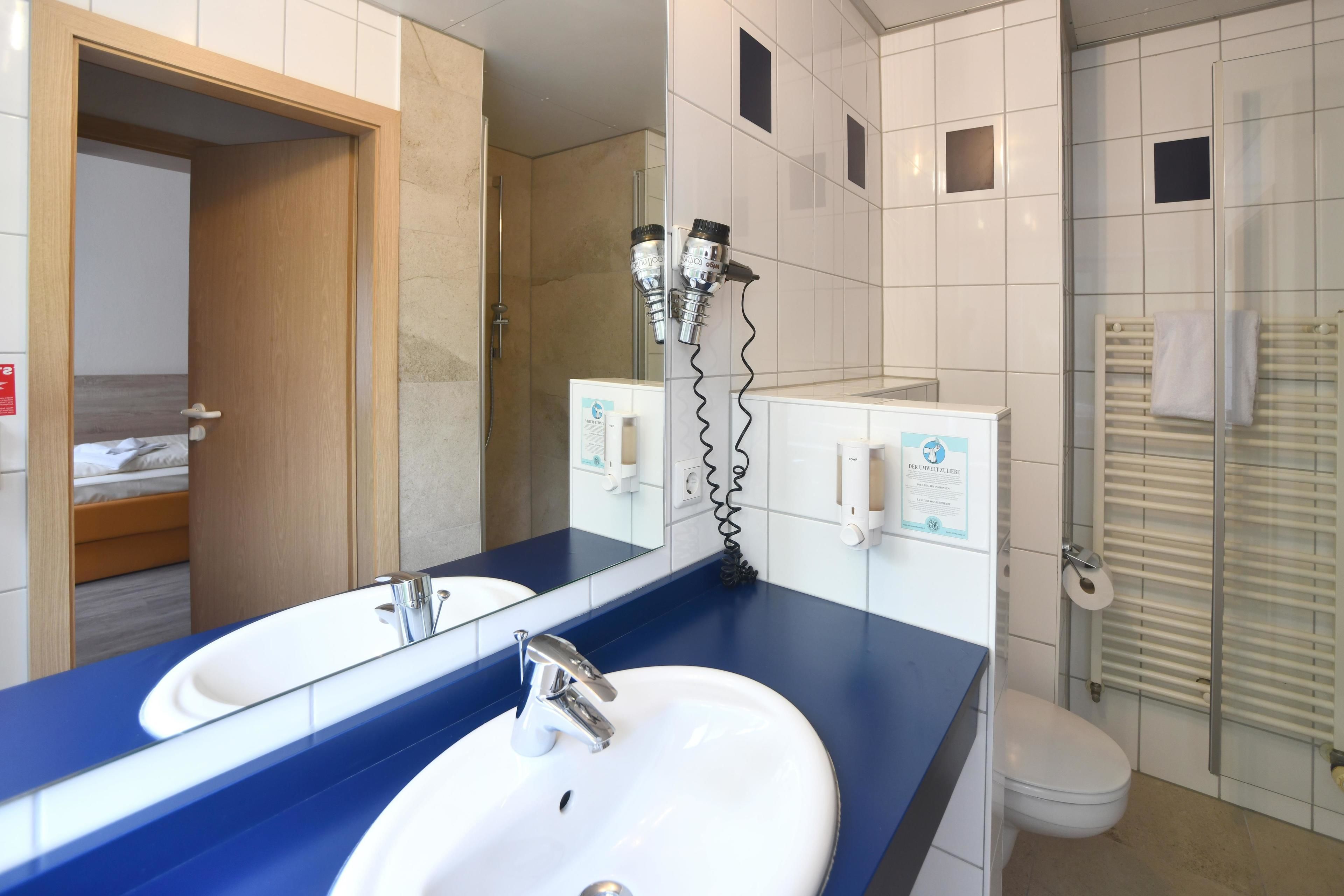Un baño con dos lavamanos, un espejo y una zona de ducha.