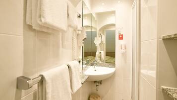 Un baño con lavamanos, espejo, toallero y zona de ducha.