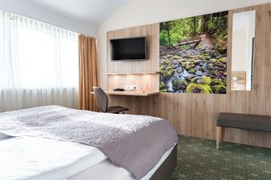 A hotel room with a bed, a desk, a TV, and a large window with curtains.