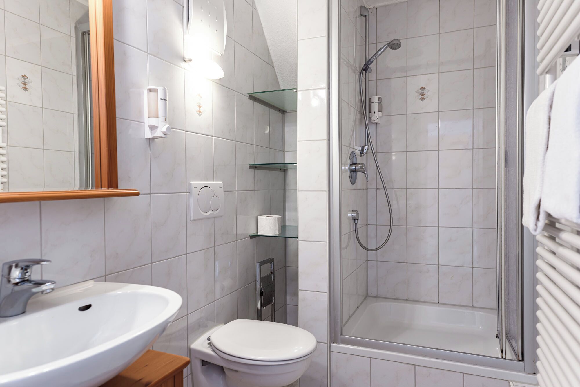 A modern bathroom with a white sink, toilet, and shower area.