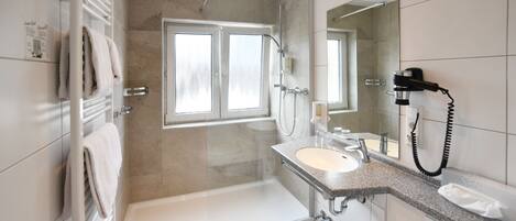 A modern bathroom with a bathtub, shower, and sink.