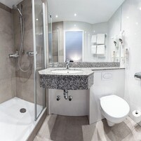 A modern bathroom with a shower, toilet, and sink.
