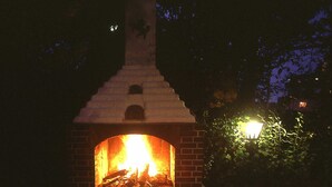 An outdoor dining area with a brick oven fireplace, surrounded by tables set for a meal. - Hotel Römerhof (Stuttgart)