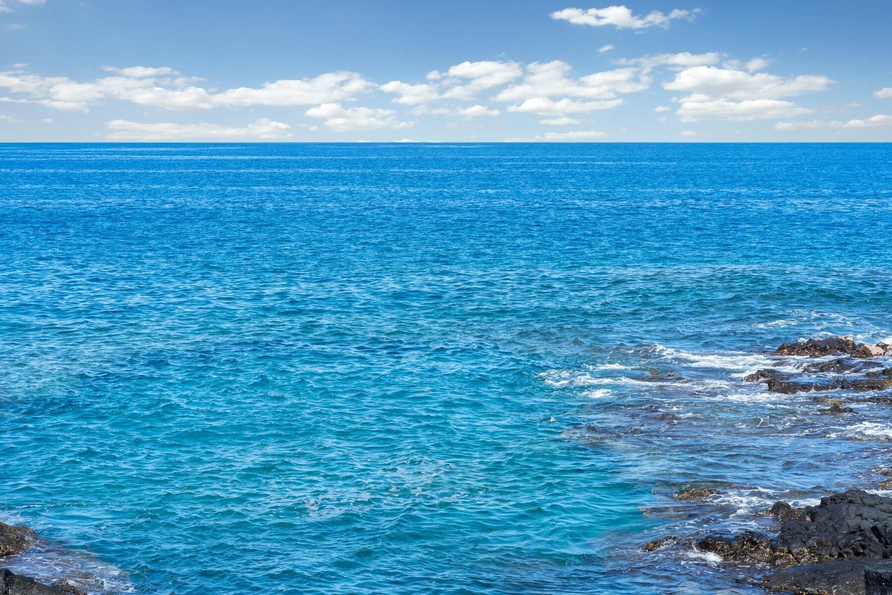 A coastal view with clear blue waters and rocky shoreline.