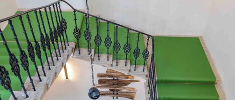 A hotel staircase with green steps and black railings.