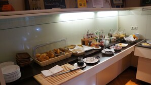 A buffet counter with various food items, including bread, pastries, and condiments. - Hotel Kulinarium an der Glems (Stuttgart)