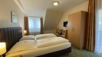 Een hotelkamer met een groot bed, een bureau, een stoel, een televisie en een kledingkast.