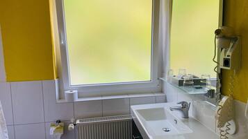 A bathroom with a window, a sink, a mirror, and a radiator.