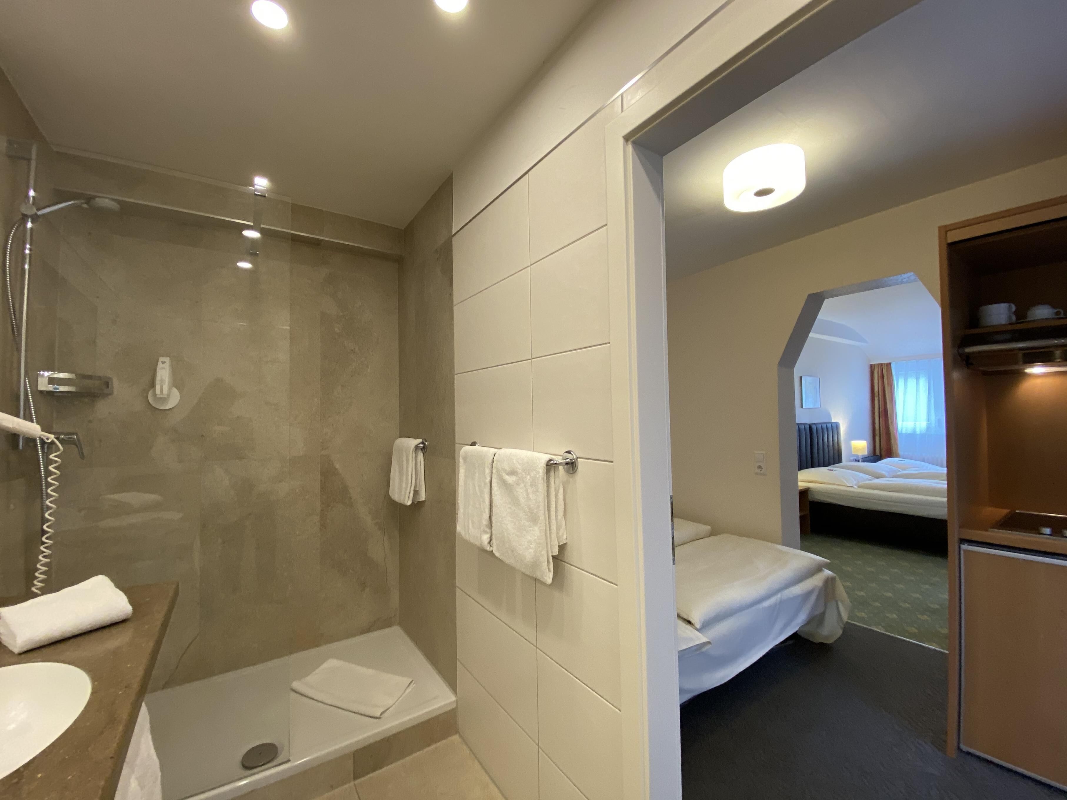 Un baño de hotel con ducha, lavamanos y barra para toallas.