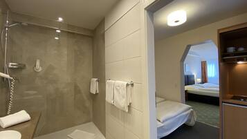 Un baño de hotel con ducha, lavamanos y barra para toallas.