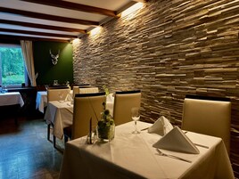 Un restaurante con paredes de piedra, manteles blancos y sillas color beige.